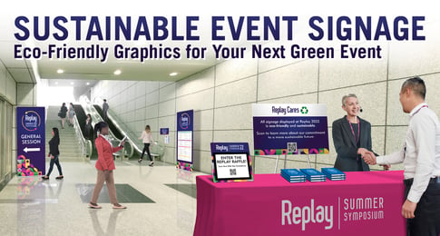 A woman at a registration desk greets a man by shaking his hand.  Assorted event materials are on the registration table including a tabletop sign and agendas.  In the background, event attendees explore the venue that is populated with retractable banners.